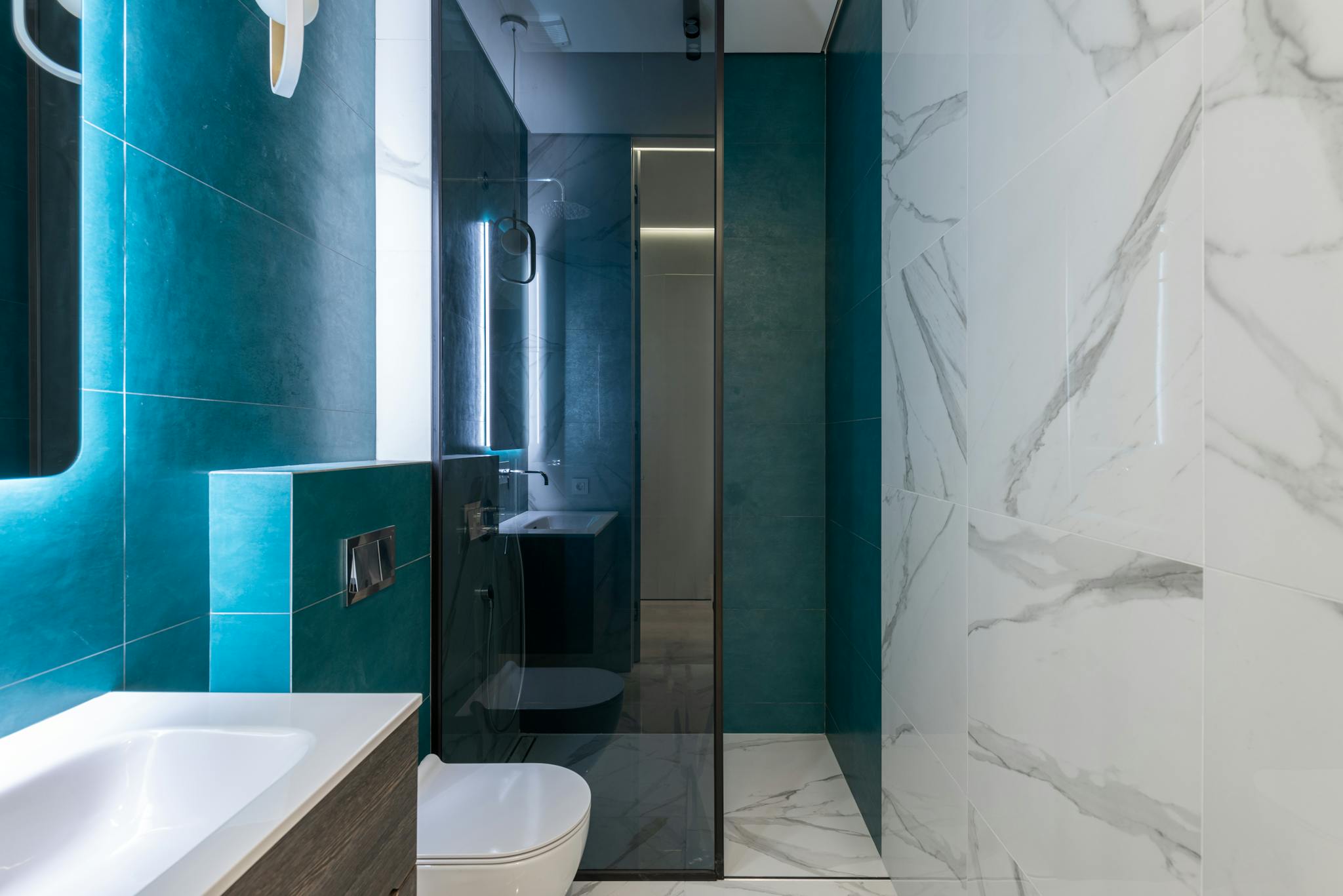 Sleek and stylish minimalist bathroom featuring teal tiles and marble accents.